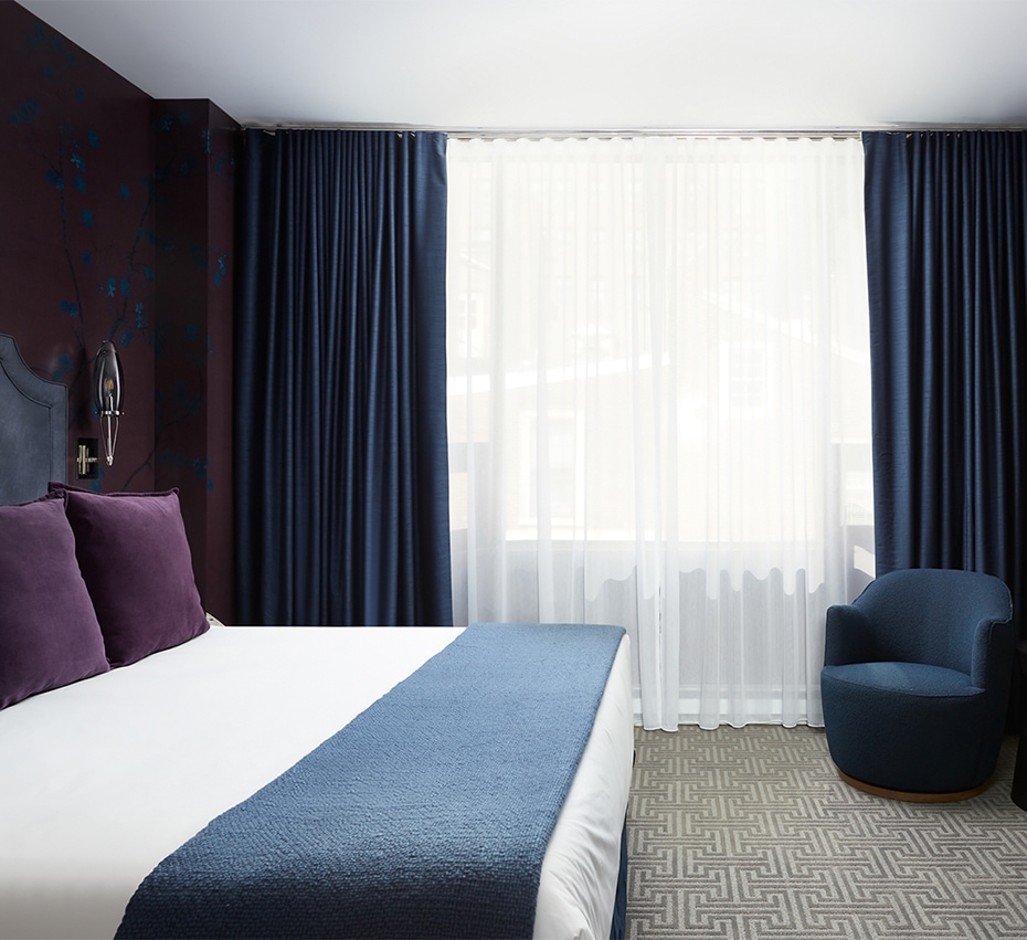 Post image for a bed with purple pillows and a chair in a room