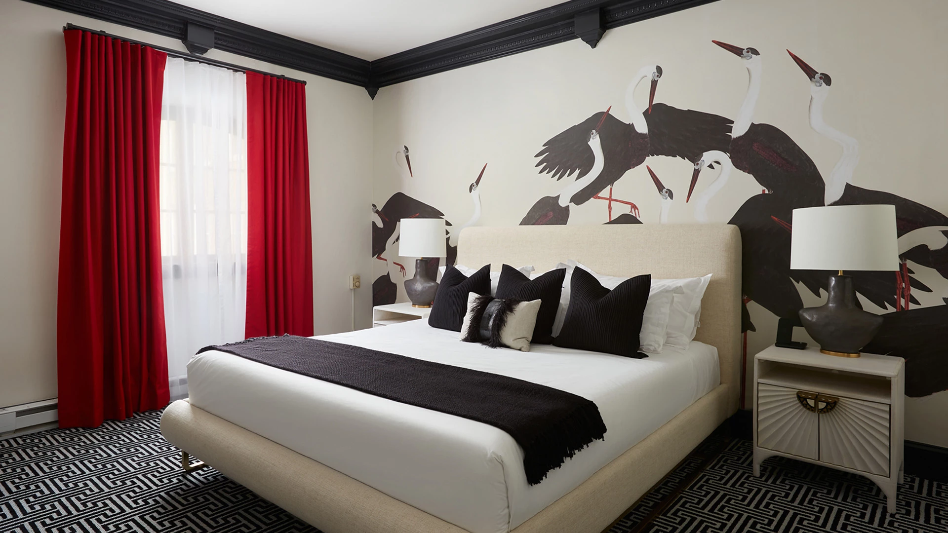 A luxurious hotel room with a king-sized bed, nightstands, lamps, and a large wall mural featuring cranes.