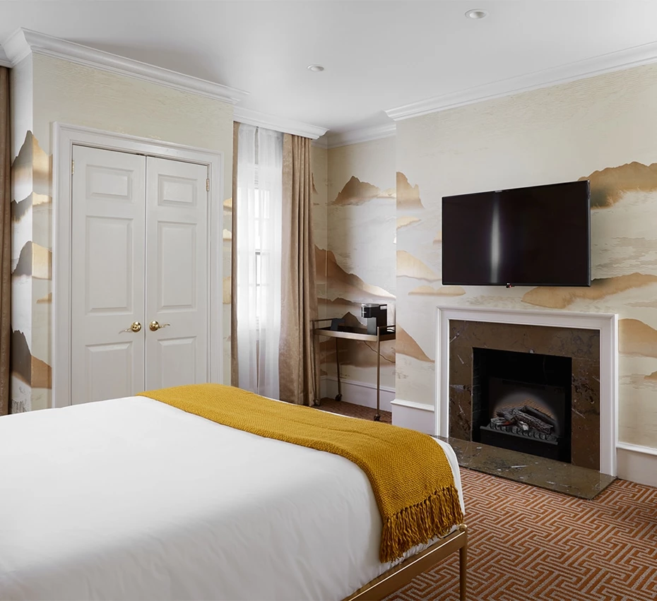 A hotel room with a bed, fireplace, and TV