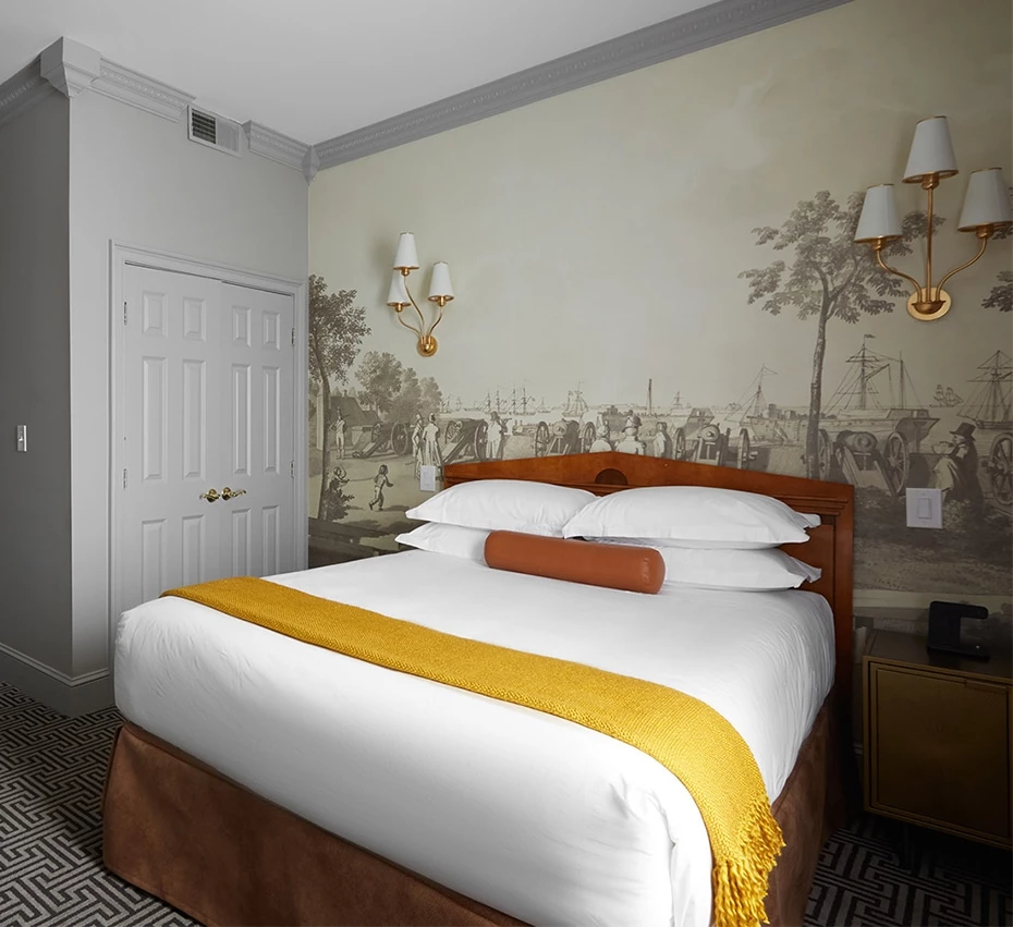 A deluxe hotel room with a king-sized bed, wallpaper, and a nightstand.