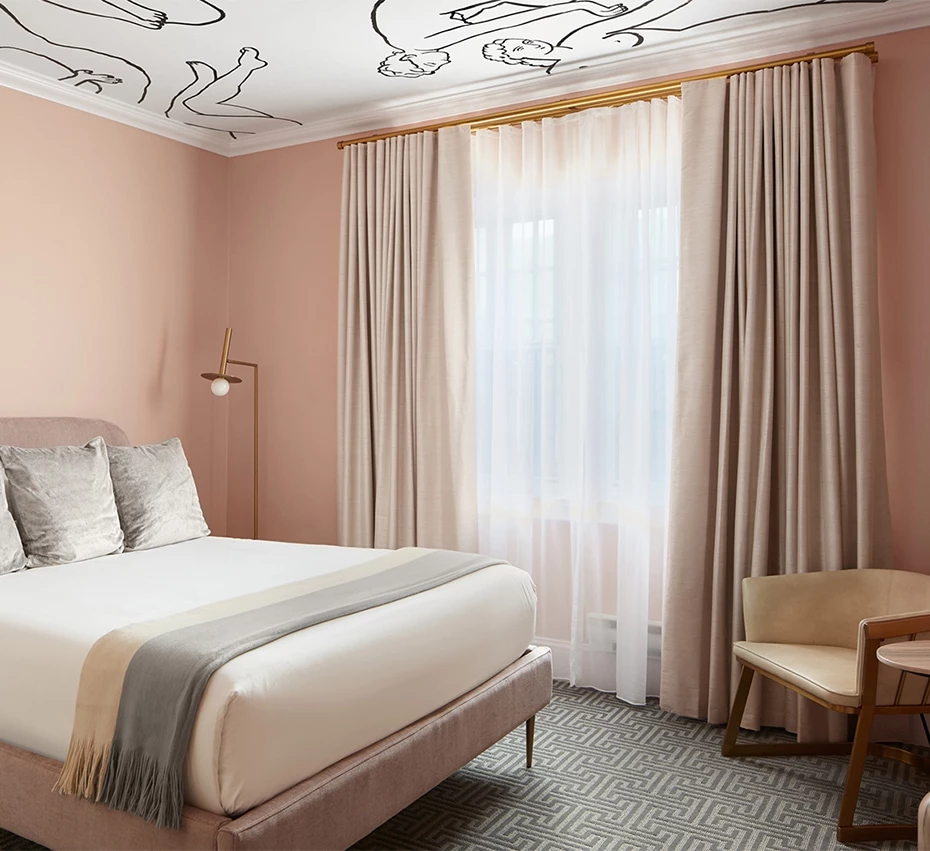 A wide view of a deluxe hotel room with a bed, chair, and window
