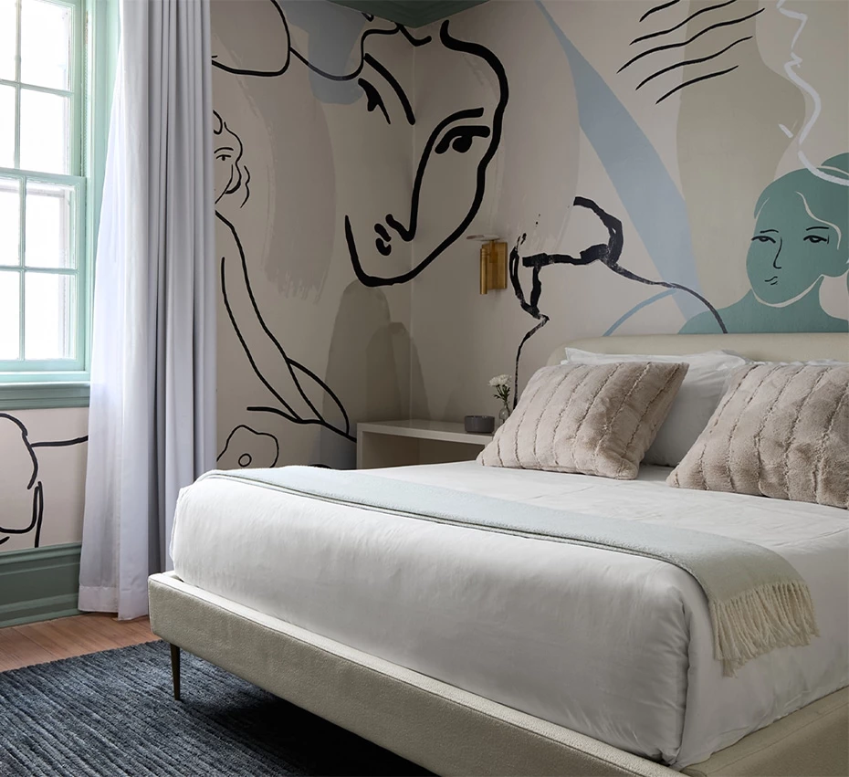 A bedroom with a large bed, a window, and a unique mural on the wall.