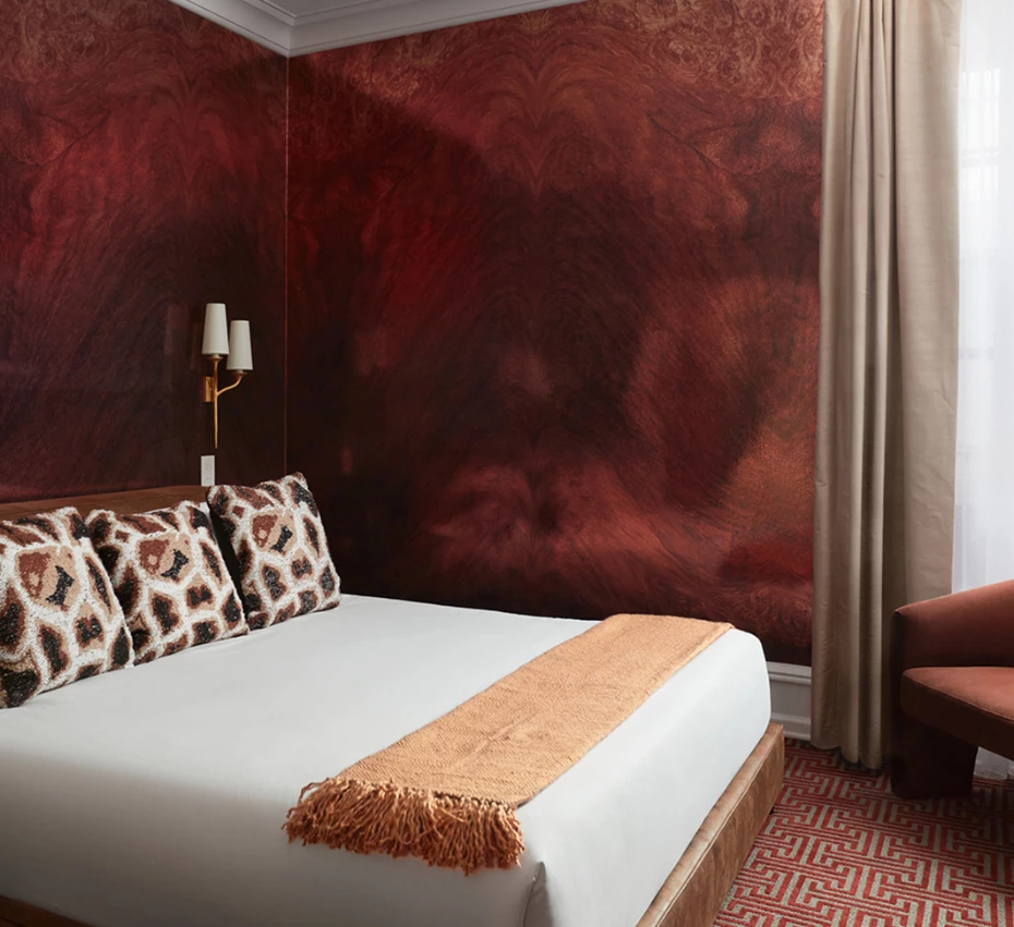 A hotel room with a large bed, patterned carpet, and window with curtains.