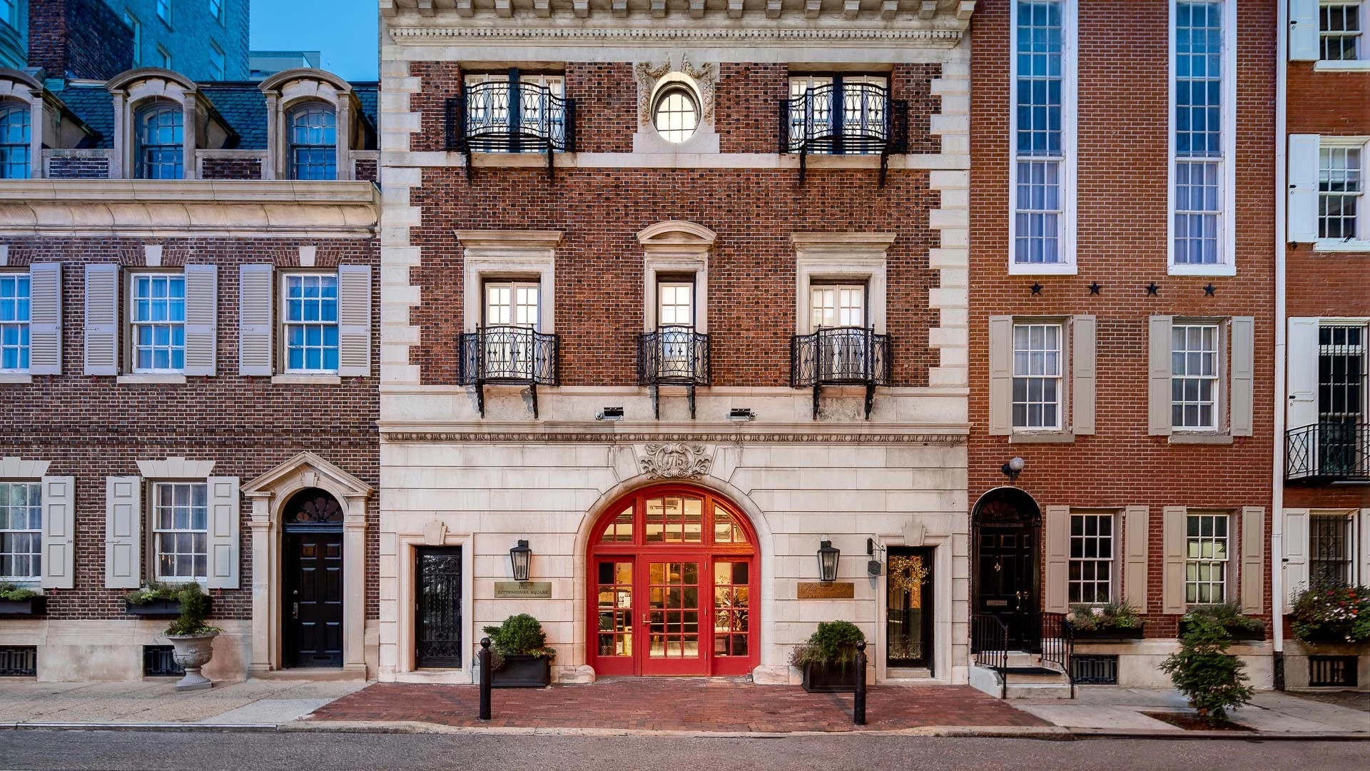A red brick building with white stone accents and a red door