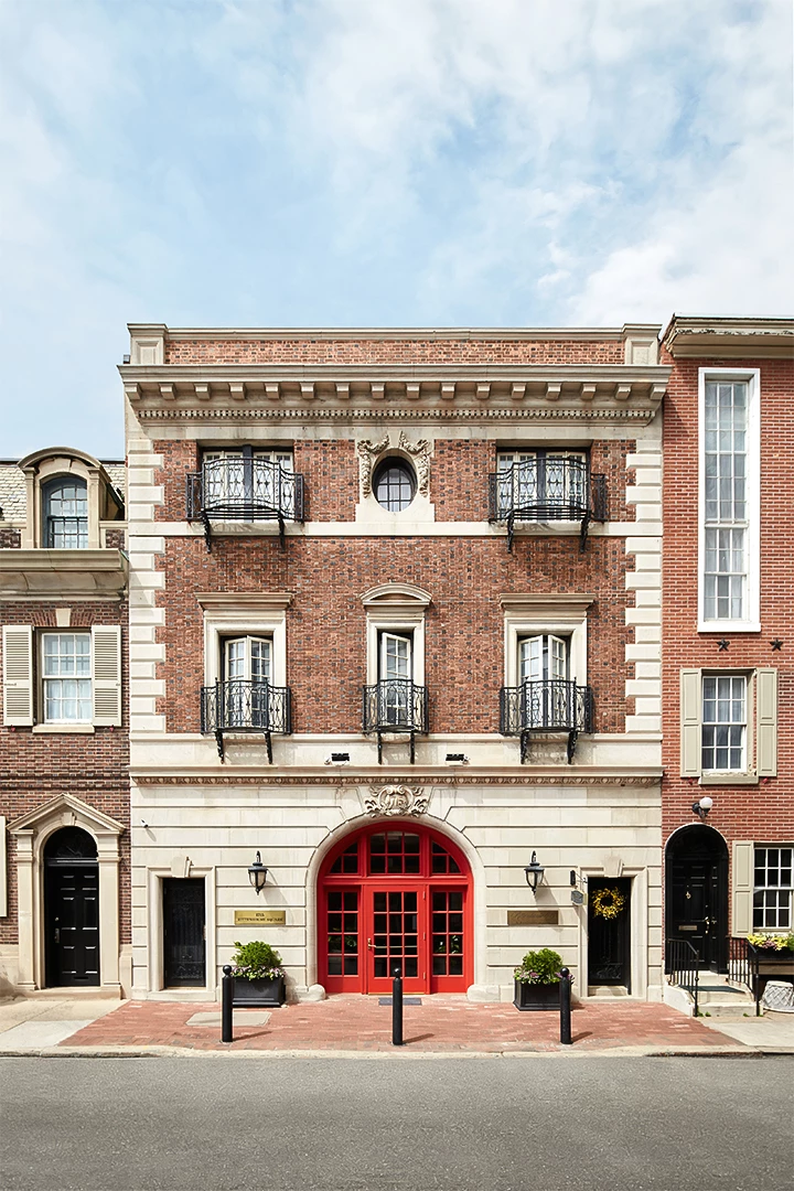 A three-story brick building with a red door and balconies