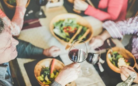 A group of people enjoying a meal and wine at a table.