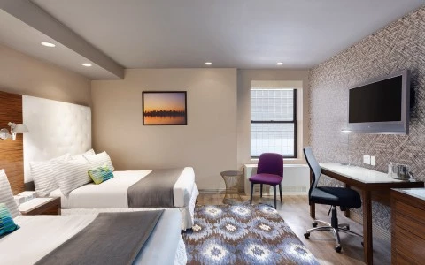 A hotel room with two beds, a desk, and a window