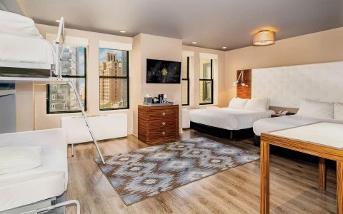 A wide view of a hotel room with two beds, a bunk bed, and a TV