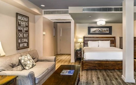 A wide view of a hotel room with a sofa, coffee table, king-sized bed, and artwork.