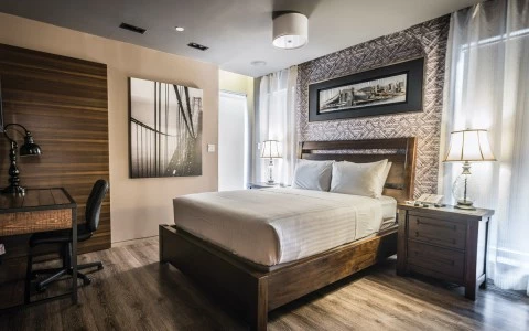 A wide view of a guest room with a large bed, desk, and chair.