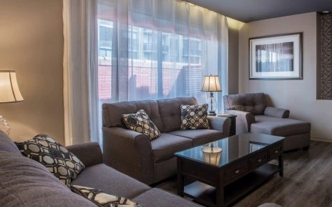 A seating area with a sofa, armchair, coffee table, and lamps.