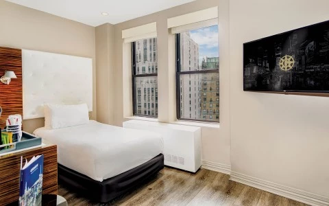 A hotel room with a bed, window, TV, and desk.