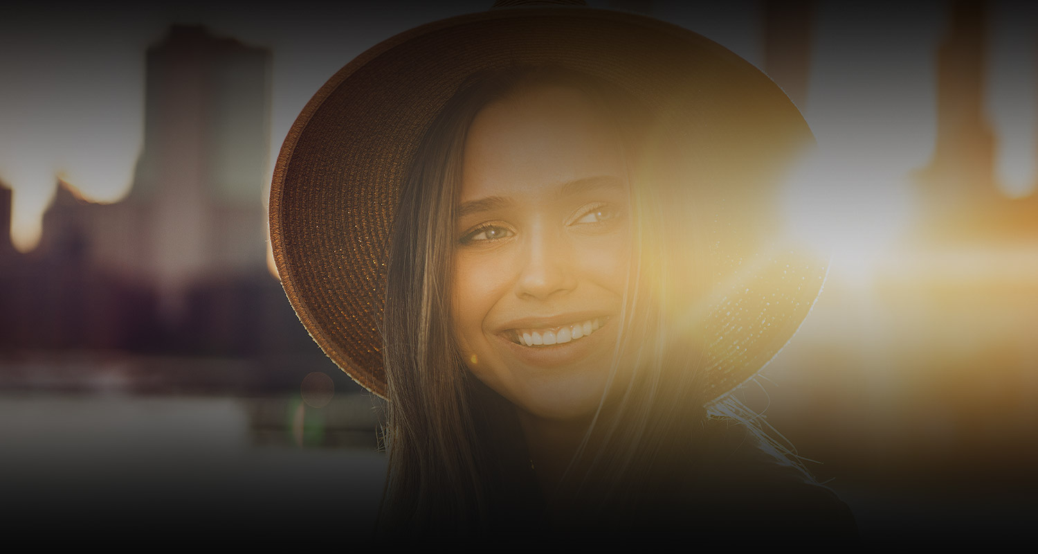 woman smiling with a sun flare on the left of the image
