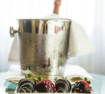 chocolate covered strawberries on a plate next to a bucket of champagne