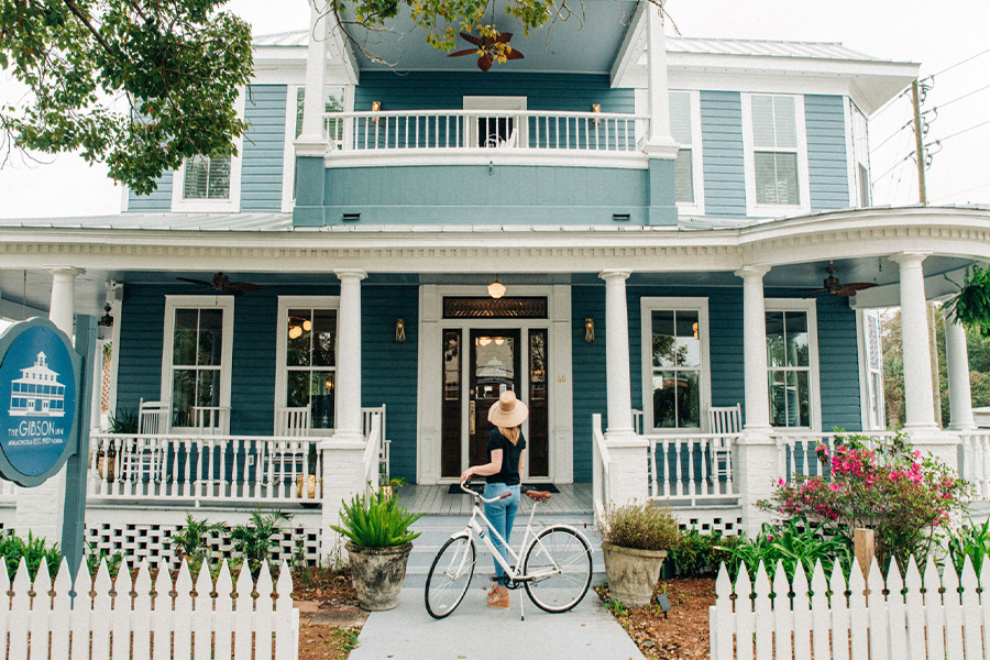 a woman standing in front of a house with a bicycle