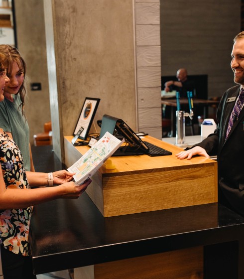 a woman handing a piece of paper to a man at a reception desk