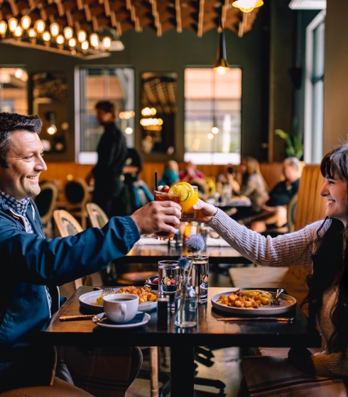 a man and woman sitting at a table with food and drinks
