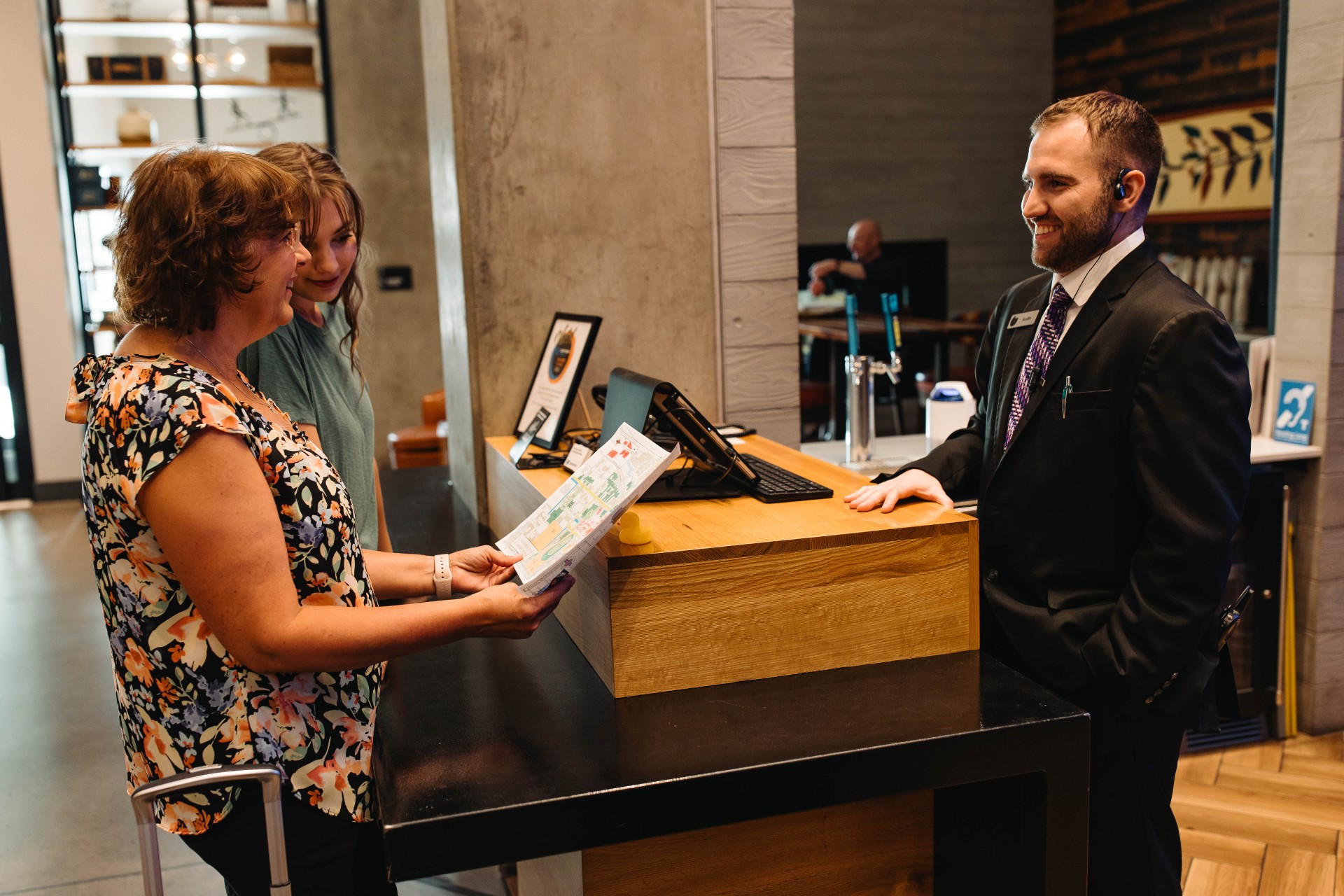 a woman handing a piece of paper to a man at a reception desk