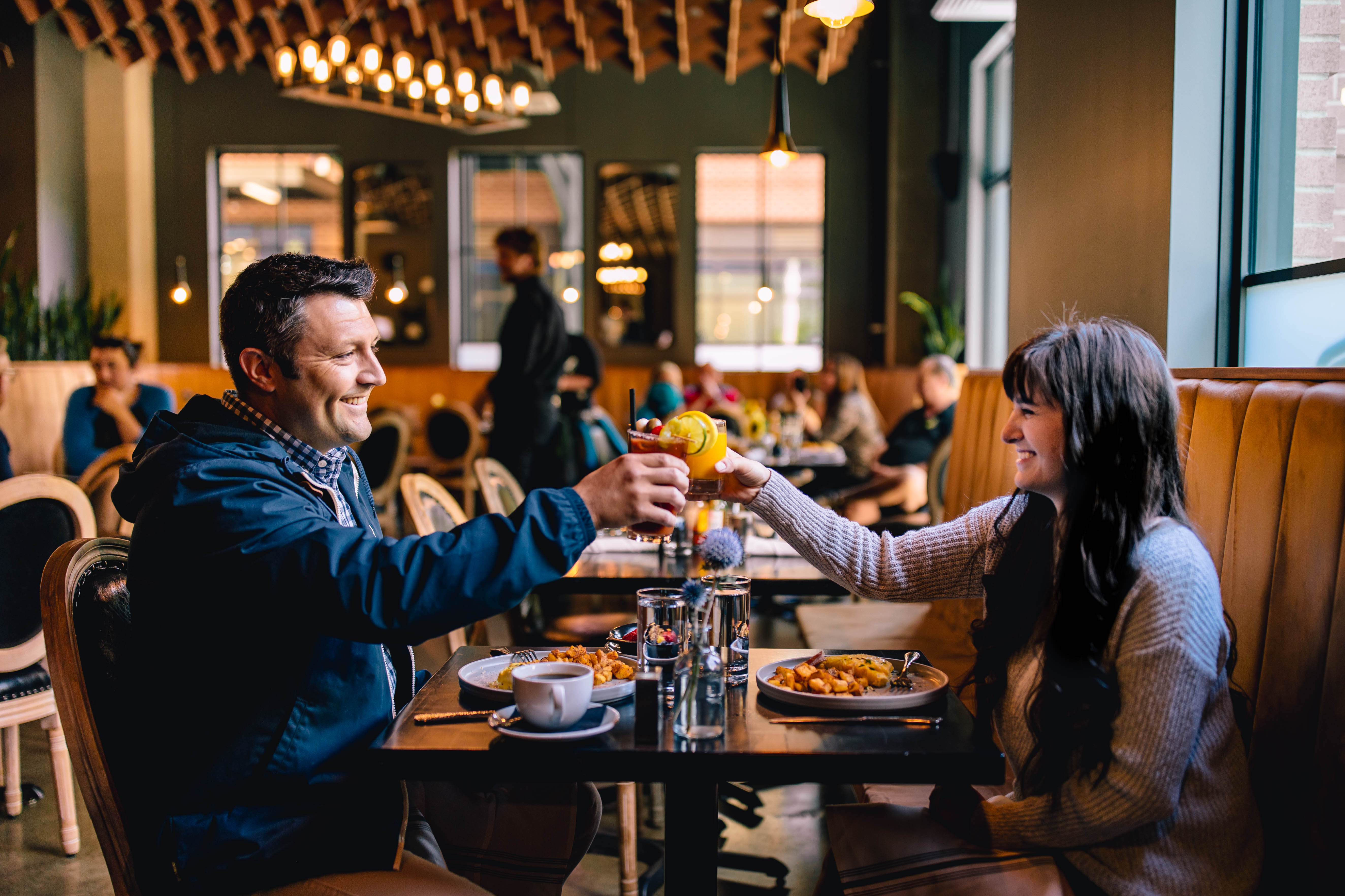 a man and woman sitting at a table with food and drinks