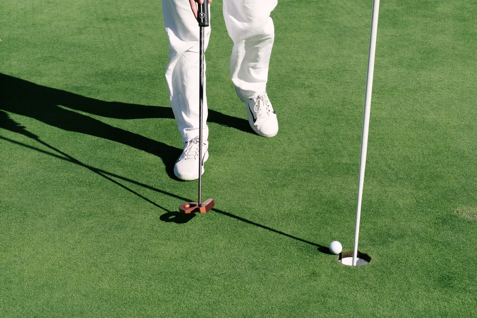 a person putting a golf ball into the hole