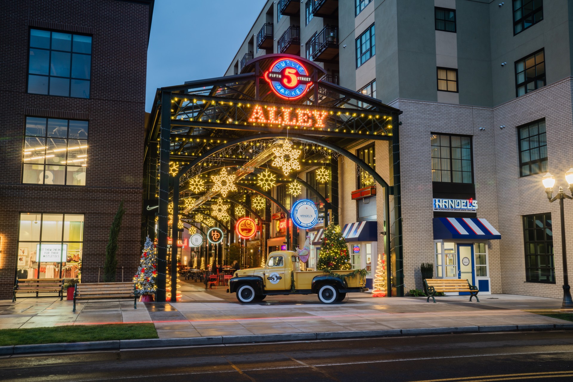 a yellow truck parked in front of a building with christmas lights