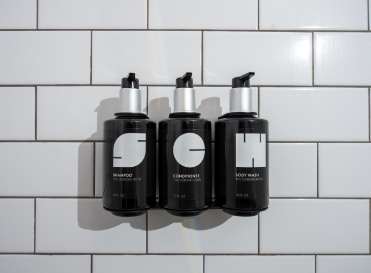 a group of black bottles with white labels on a white tile wall