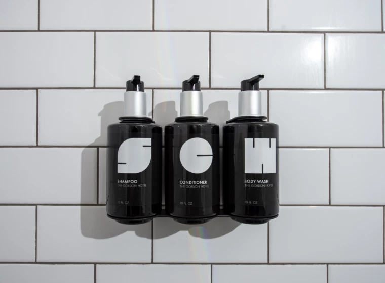 a group of black bottles with white labels on a white tile wall