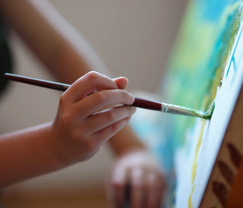 a hand holding a paintbrush and painting