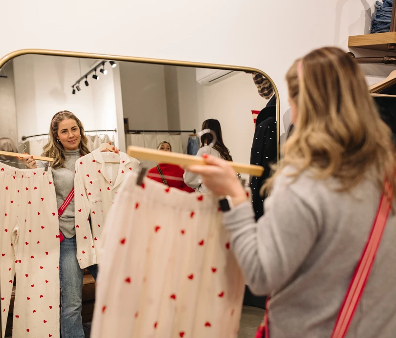 a woman looking at clothes in a mirror