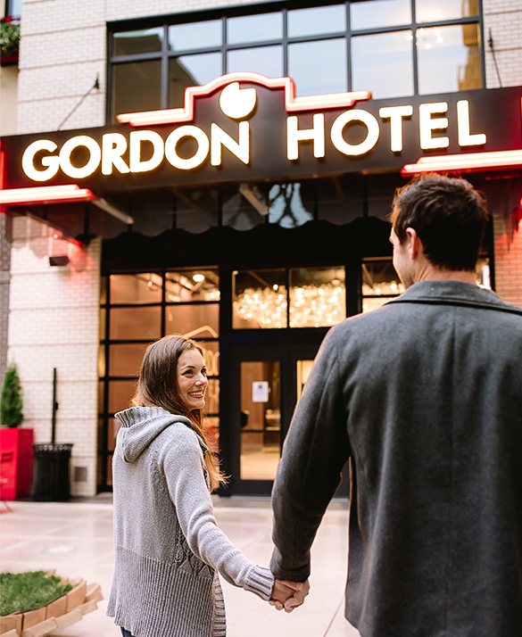 a man and woman holding hands in front of a hotel