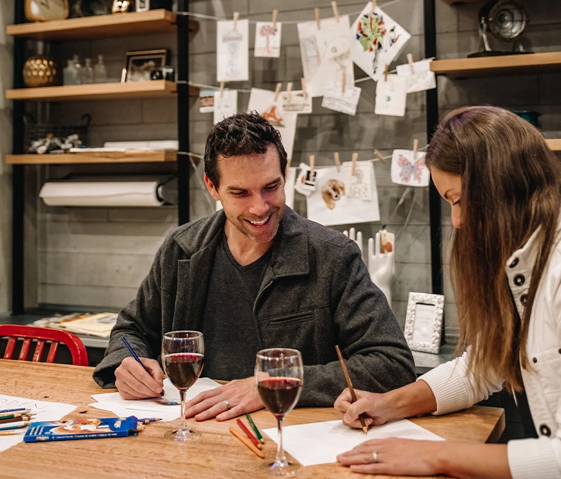 a man and woman sitting at a table writing on paper