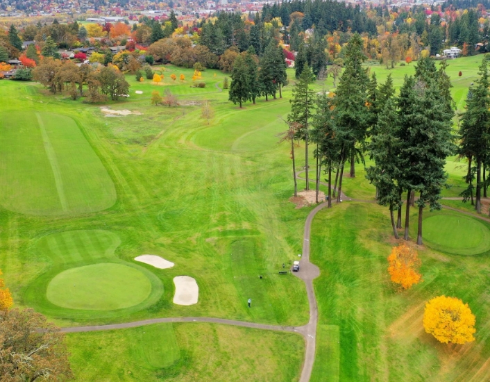 a golf course with trees and a city in the background