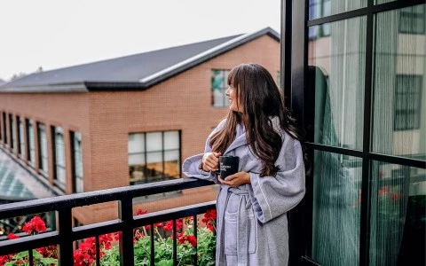 a woman standing on a balcony looking at the view with a mug in her hand