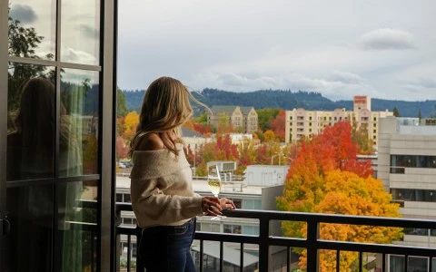 a woman with a glass of champagne standing on a balcony overlooking a city