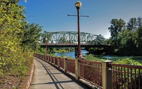 a sidewalk leading to a bridge over a river