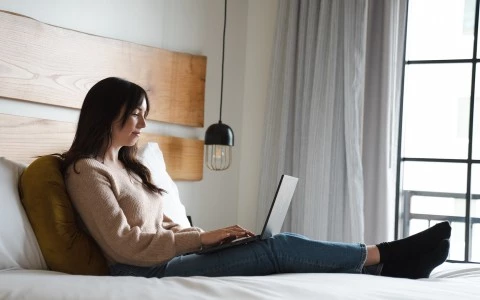 a person sitting on a bed with a laptop
