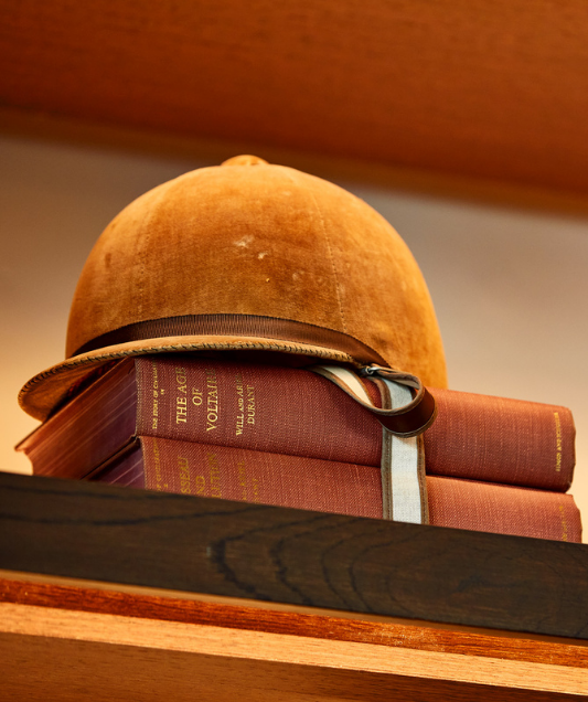 a vintage helmet on top of books on a bookshelf