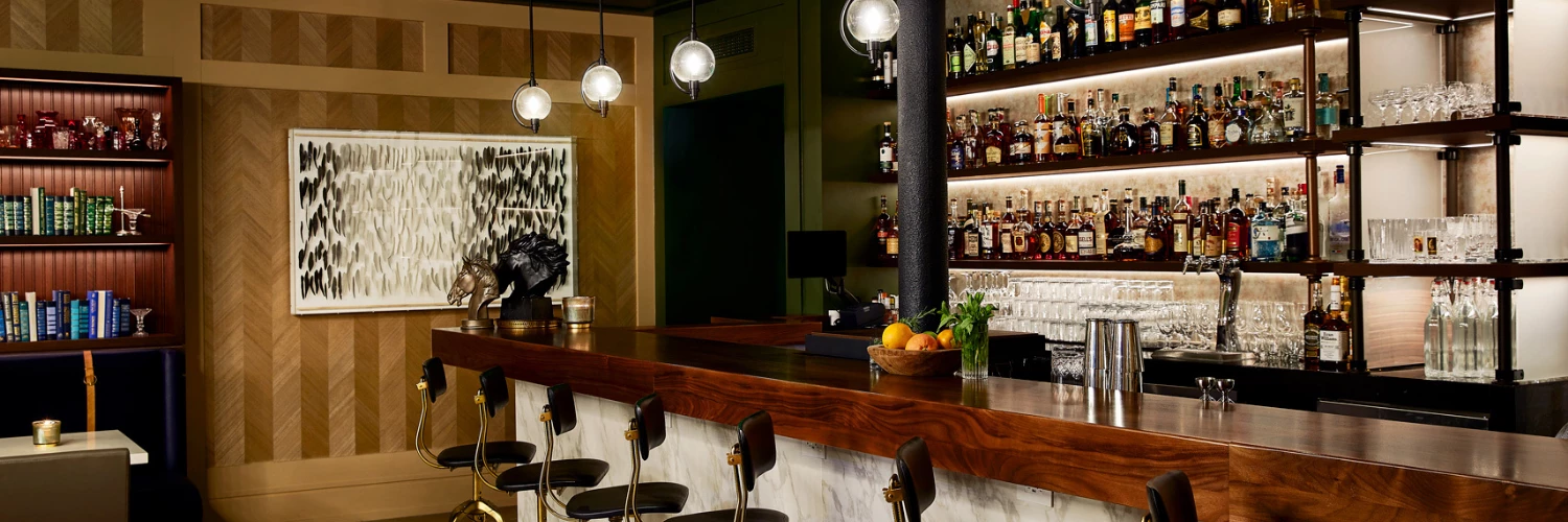 a hightop seating area at a bar with a shelf full of liquor