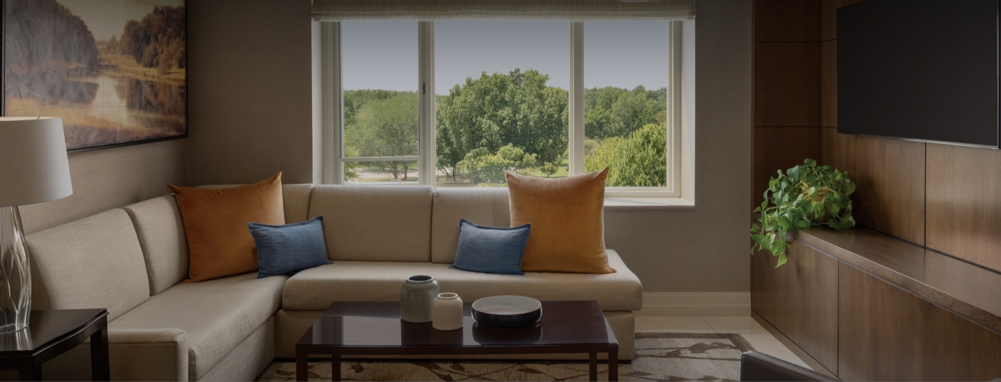 a couch with pillows and a coffee table in front of a window