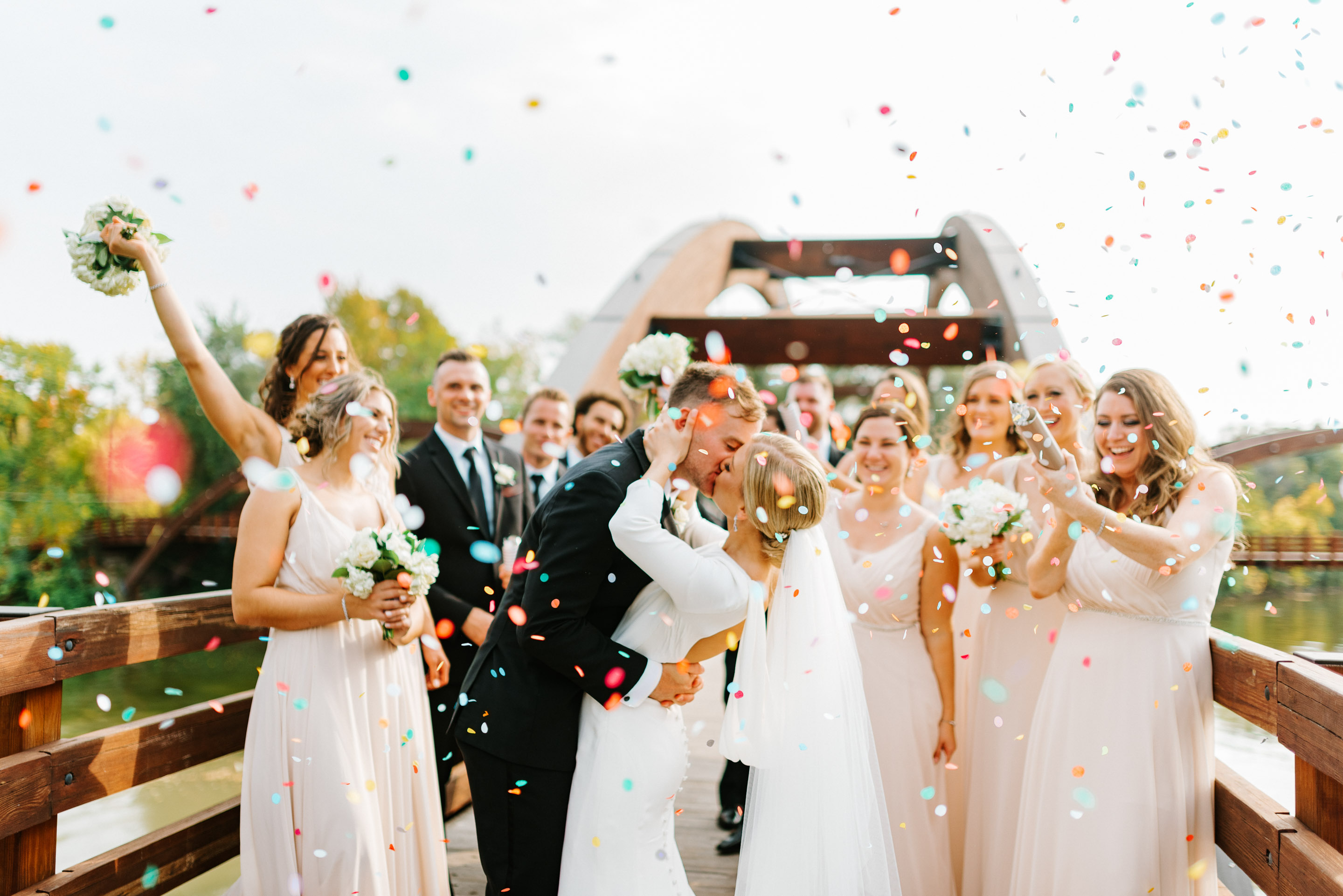 a man kissing a woman in white dresses with confetti falling