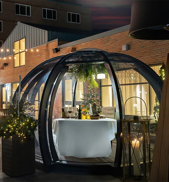 a round glass structure with a table and a tablecloth in front of a brick building