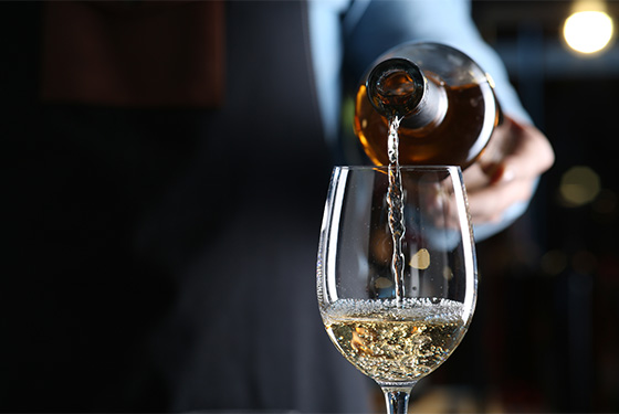 a person pouring a glass of wine