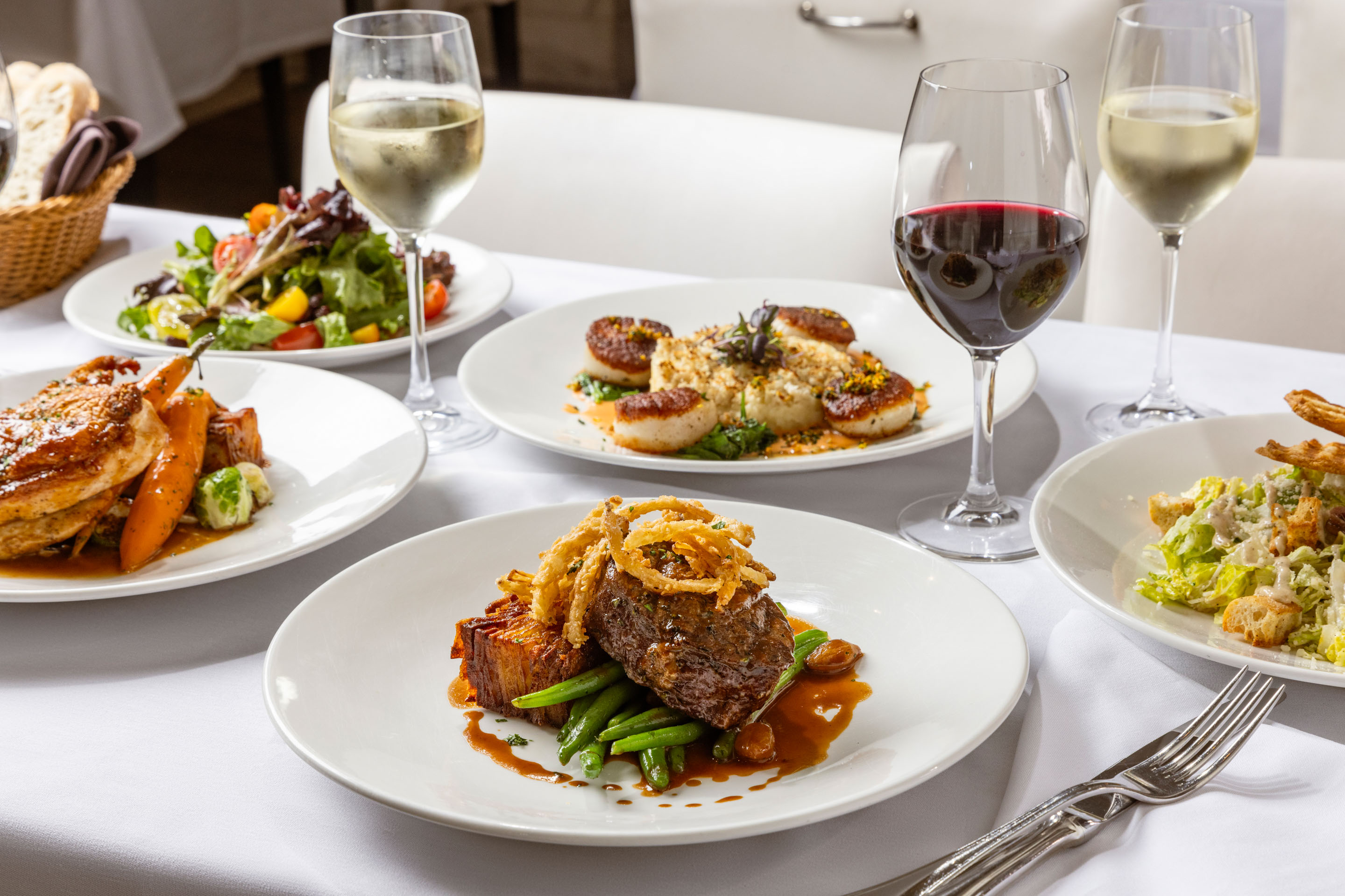a table with plates of food and wine glasses