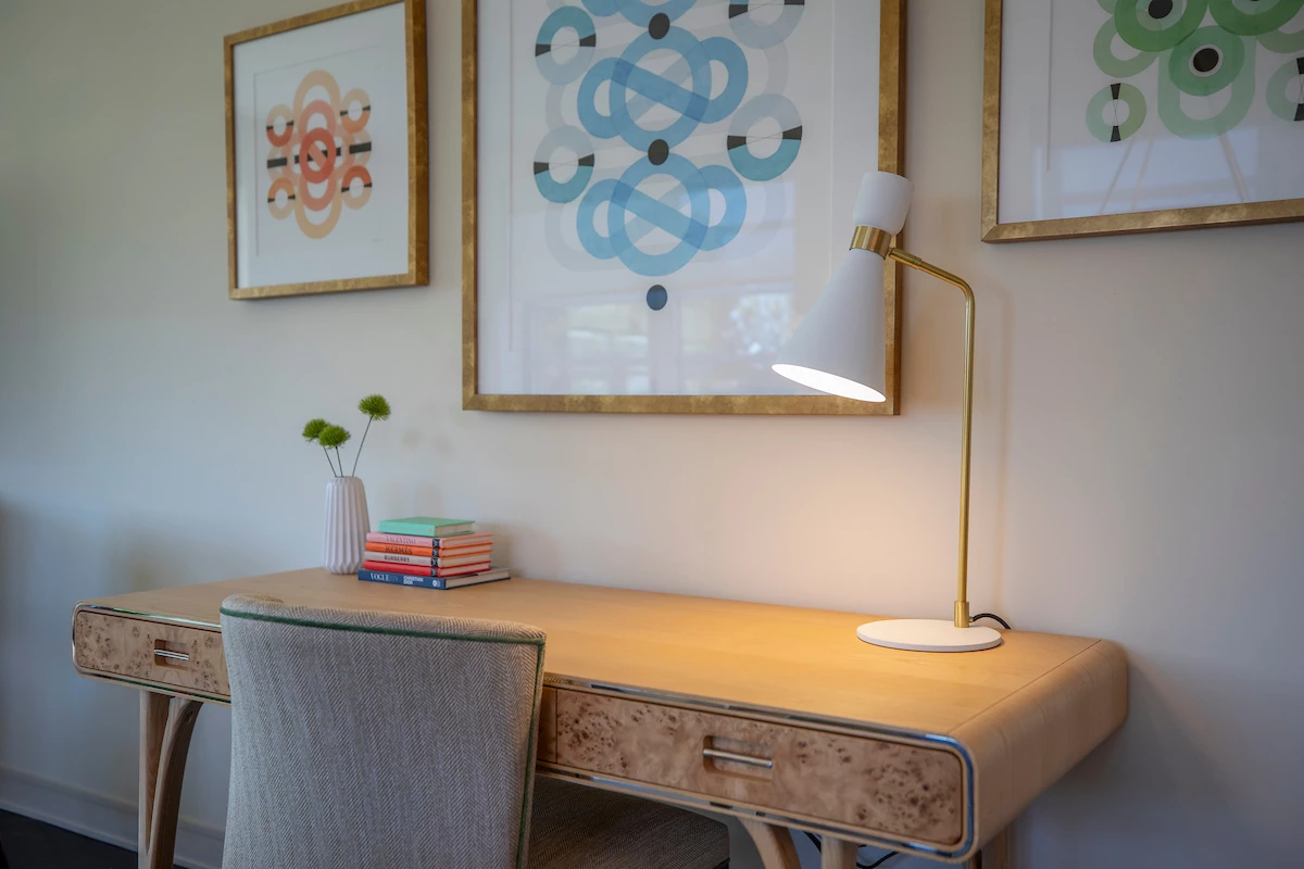 a desk with a lamp and a picture on the wall