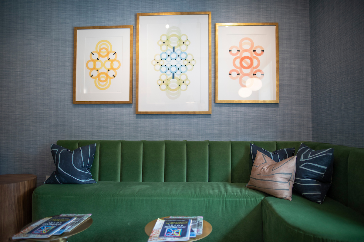 a green couch with pillows and a coffee table with art on the wall