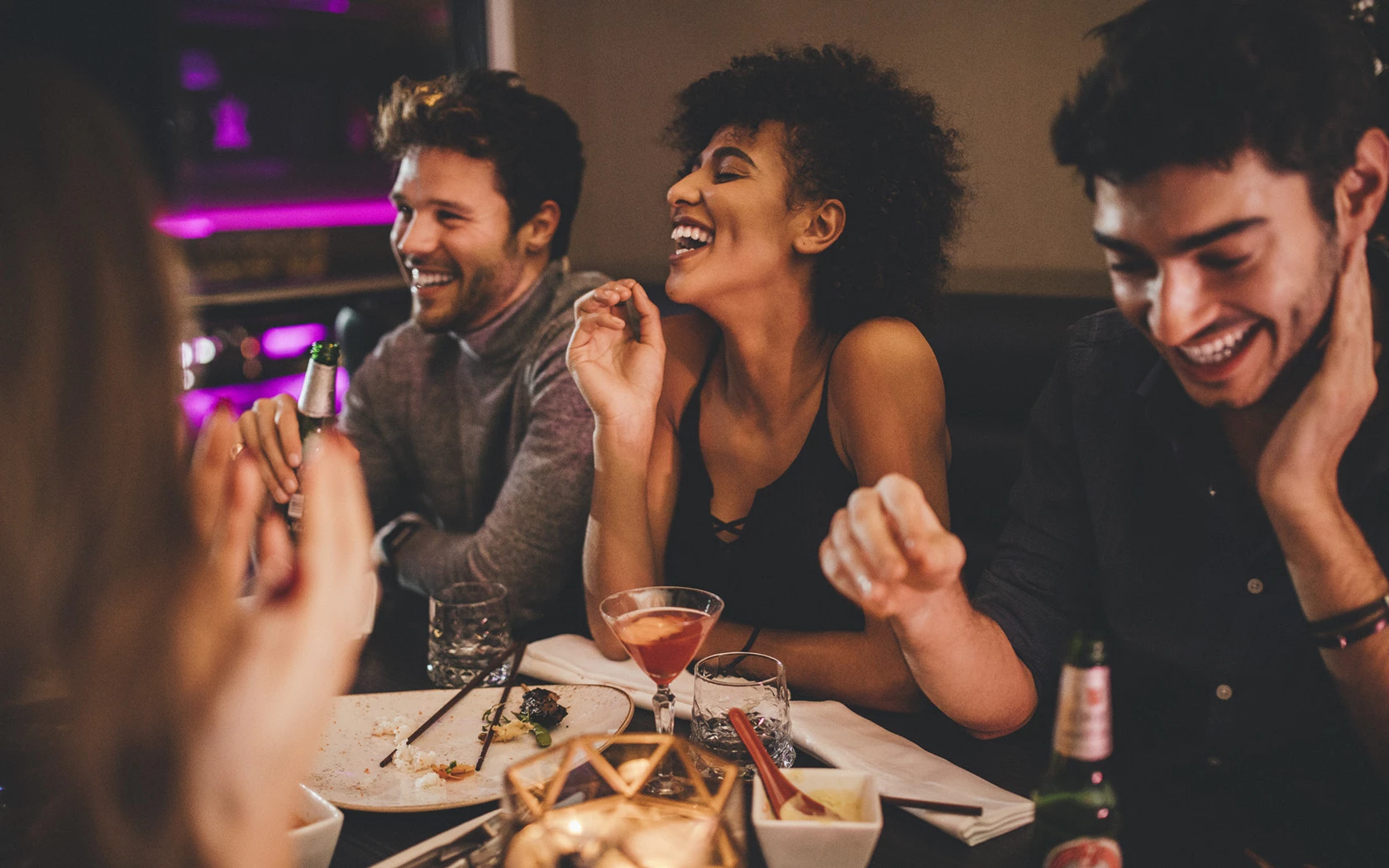 a group of people sitting at a table with food and drinks