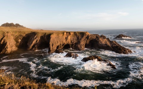a rocky cliff with waves crashing on it