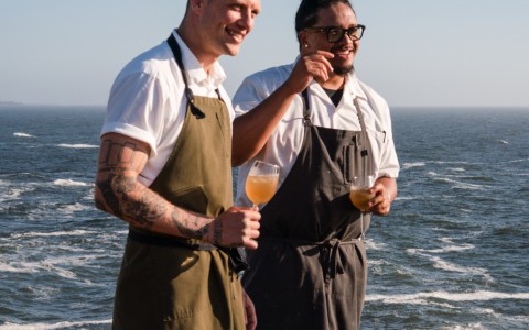 two men wearing aprons standing by the ocean