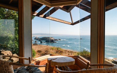 a view of the ocean from a room with a table and chairs