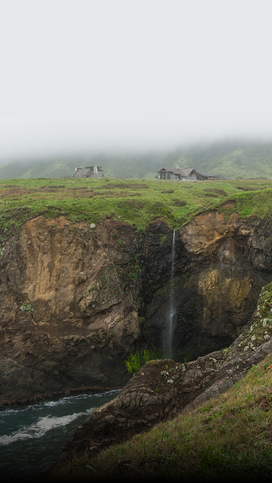 a waterfall and a house on a cliff